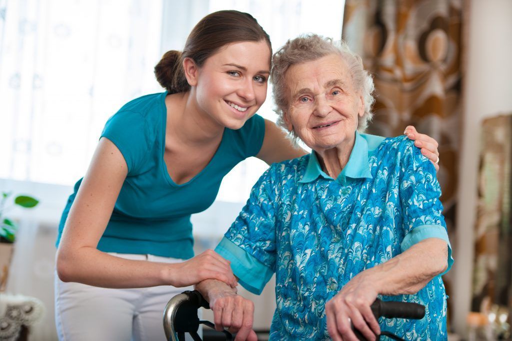 A person supporting an older wheelchair user at home