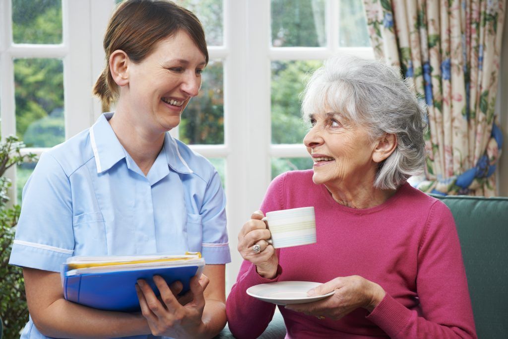 A care worker in conversation with an older woman over tea