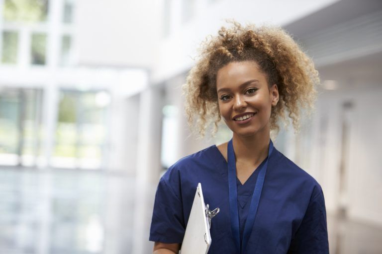 A healthcare worker smiling in a workplace corridor