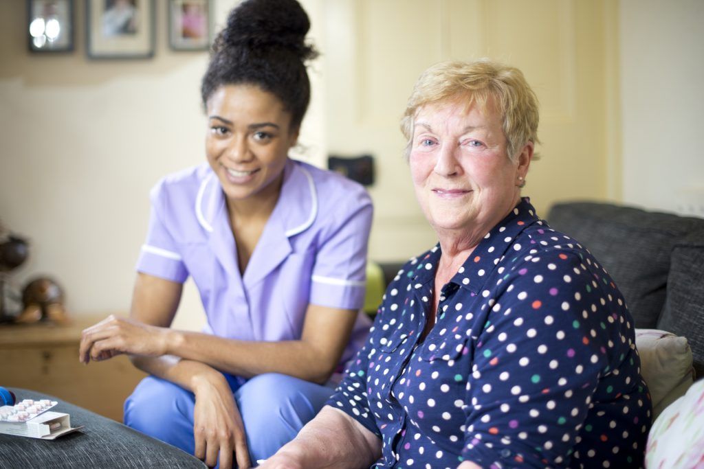 Care professional speaking with an older woman seated at home