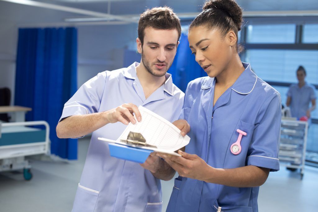 Two healthcare professionals consulting workplace information
