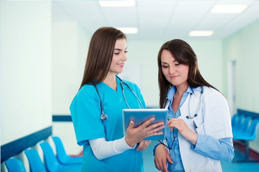 Two healthcare workers reviewing a tablet